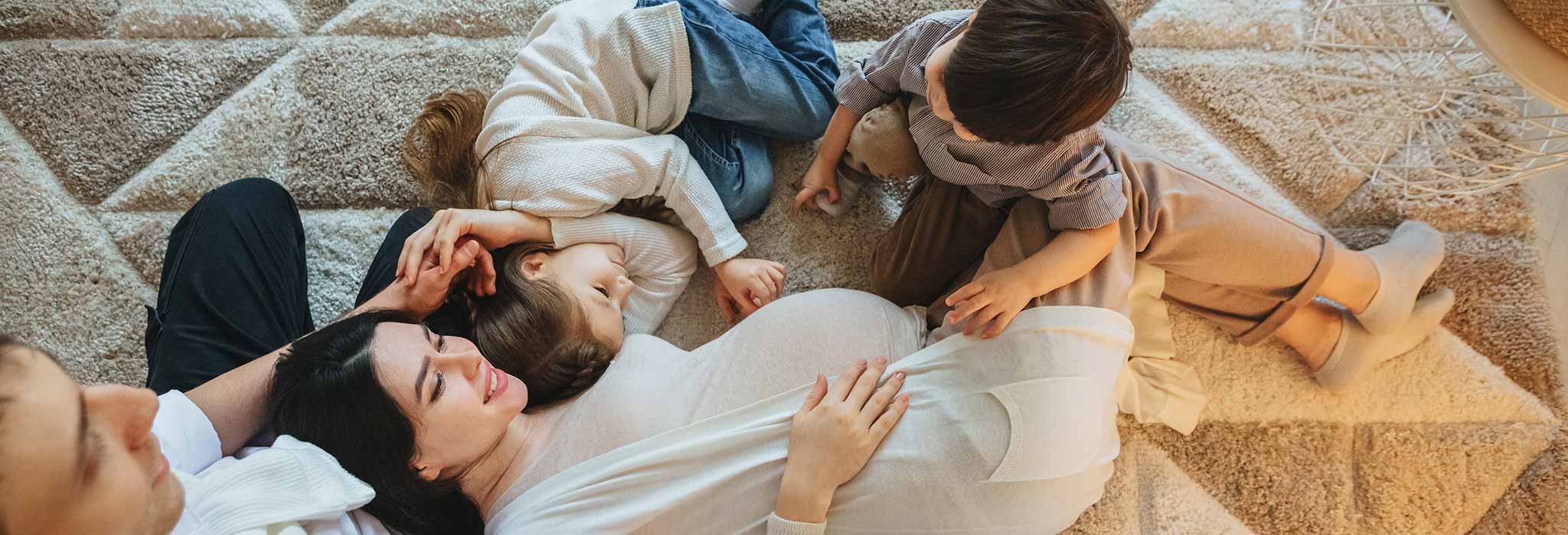 Família junta al sofà amb dos fills i dona embarassada